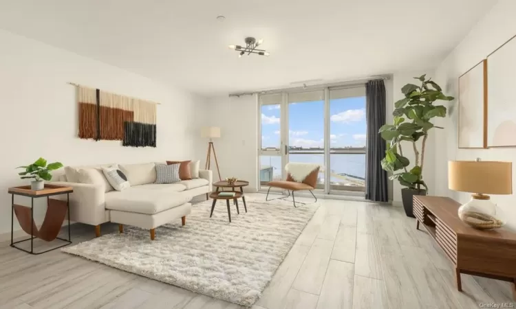 Living room featuring a water view, a wall of windows, and light hardwood / wood-style floors