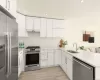 Kitchen with white cabinets, appliances with stainless steel finishes, kitchen peninsula, and sink