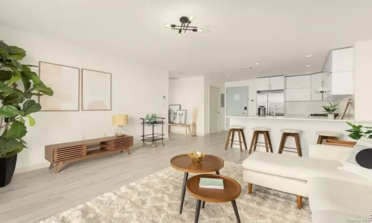 Living room with a notable chandelier, light wood-type flooring, and sink