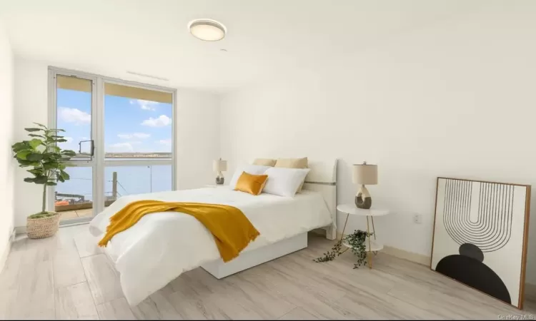 Bedroom featuring floor to ceiling windows, a water view, and light wood-type flooring