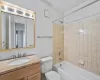 Full bathroom featuring tiled shower / bath combo, toilet, a textured ceiling, and vanity