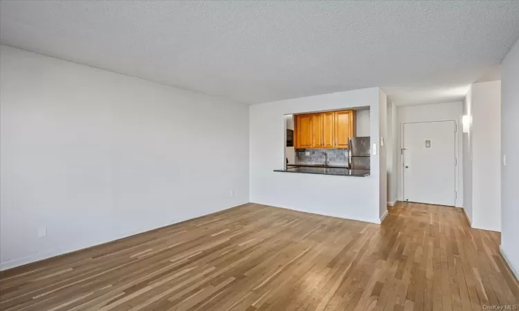 Unfurnished living room with a textured ceiling, light hardwood / wood-style flooring, and sink