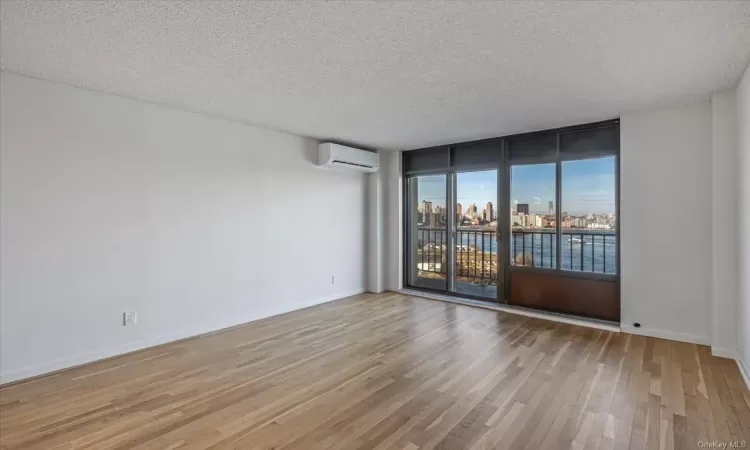 Empty room featuring light hardwood / wood-style floors, a textured ceiling, and a wall unit AC