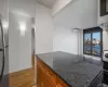 Kitchen with a wall mounted air conditioner, light hardwood / wood-style flooring, dark stone countertops, stainless steel fridge, and a textured ceiling