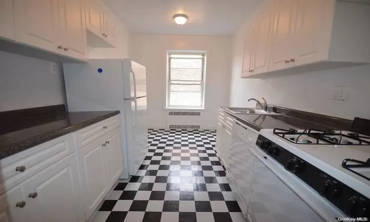 Kitchen with light stone counters, sink, white cabinetry, and stainless steel appliances