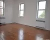 Unfurnished room featuring radiator, a healthy amount of sunlight, and hardwood / wood-style floors