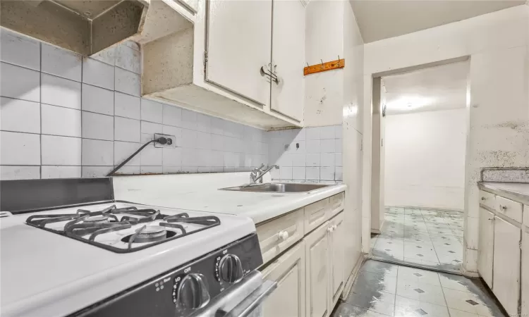 Kitchen featuring light hardwood / wood-style floors, crown molding, gas stove, and decorative backsplash