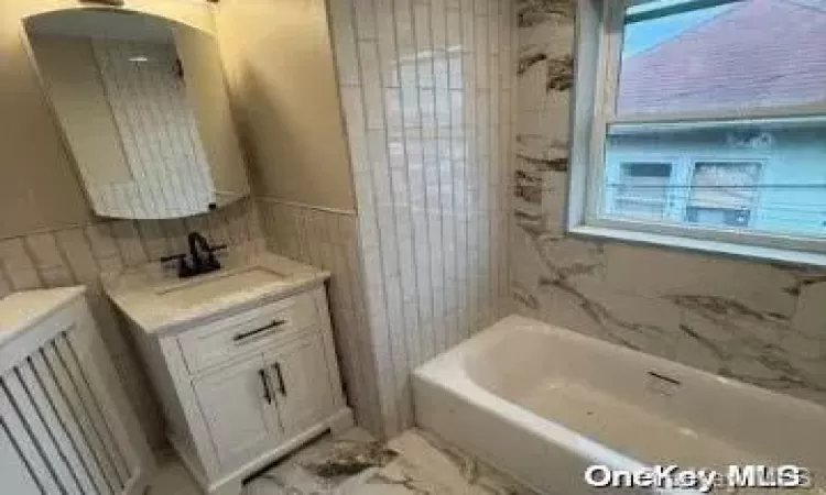 Full bathroom featuring vanity, tiled shower / bath combo, and toilet