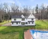 Back of property featuring a covered pool and a lawn