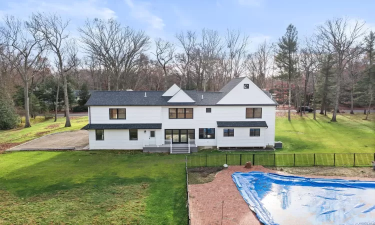 Back of property featuring a covered pool and a lawn