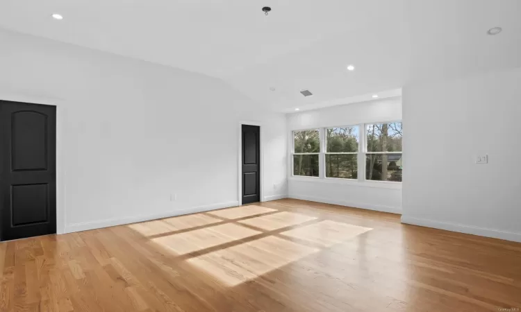 Empty room with lofted ceiling and light hardwood / wood-style flooring