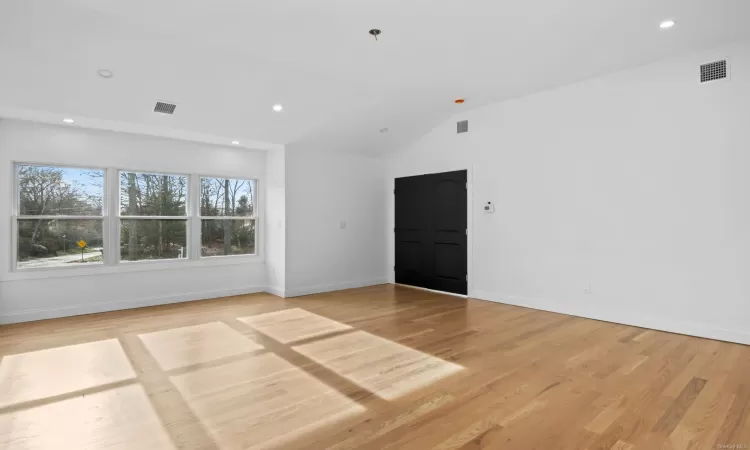 Empty room with light wood-type flooring and lofted ceiling