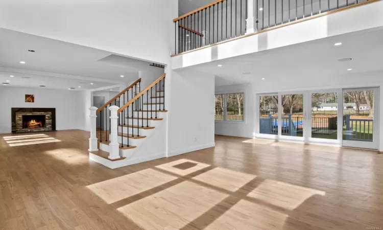 Unfurnished living room featuring a towering ceiling and light hardwood / wood-style floors