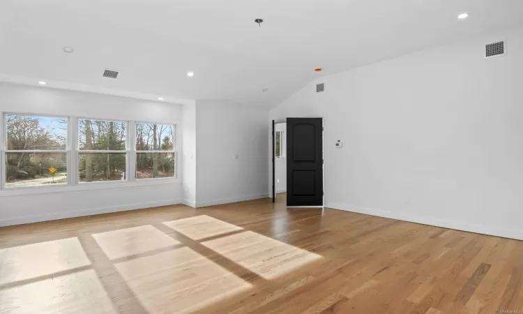 Spare room featuring light hardwood / wood-style flooring and vaulted ceiling