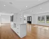 Kitchen featuring light stone countertops, a center island, french doors, white cabinets, and light wood-type flooring