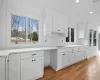 Kitchen featuring white cabinets, light wood-type flooring, and light stone countertops