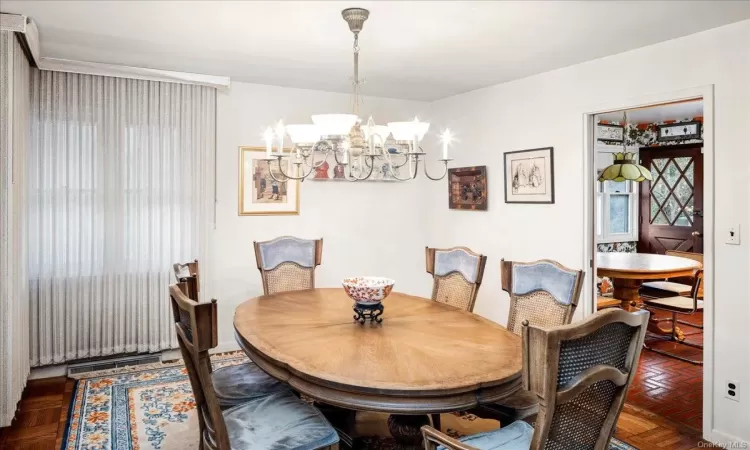 Dining space with dark parquet flooring and a chandelier