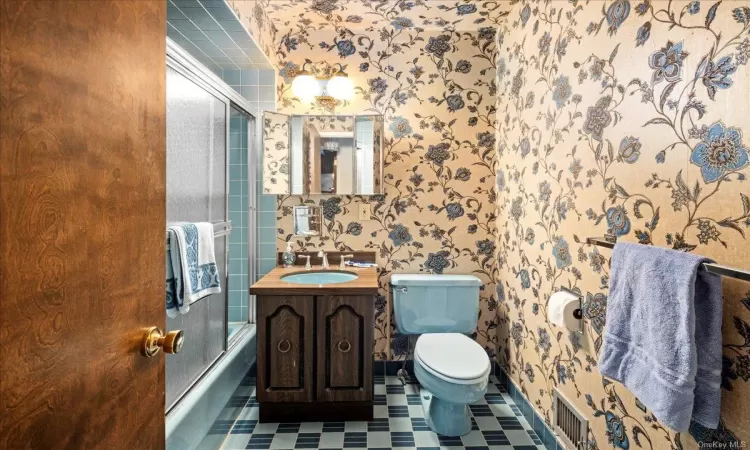 Full bathroom with vanity, toilet, and bath / shower combo with glass door