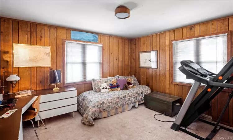 Bedroom featuring light carpet and wooden walls