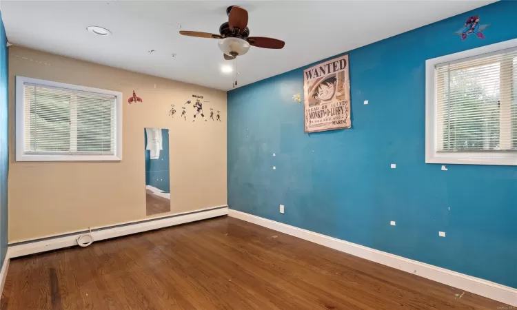 Unfurnished room with ceiling fan, a baseboard radiator, and wood-type flooring