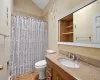 Bathroom featuring a shower with curtain, tile patterned flooring, vaulted ceiling, toilet, and vanity