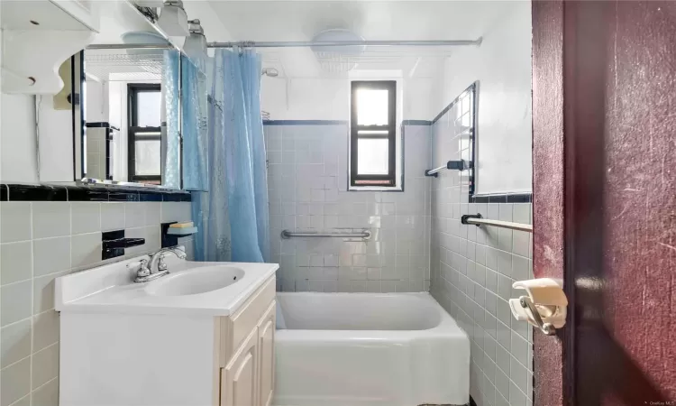 Bathroom with vanity, tile walls, and shower / tub combo