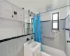 Bathroom featuring shower / bath combination with curtain, vanity, and tile walls