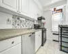 Kitchen with stainless steel dishwasher, white cabinets, black range with gas cooktop, and tasteful backsplash