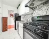 Kitchen featuring tasteful backsplash, gas stove, extractor fan, sink, and white cabinets