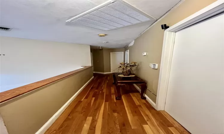 Hallway with hardwood / wood-style floors