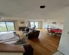 Living room with ceiling fan with notable chandelier, a tile fireplace, and light hardwood / wood-style flooring