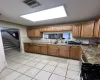 Kitchen with light tile patterned floors, sink, dark stone counters, and ornamental molding