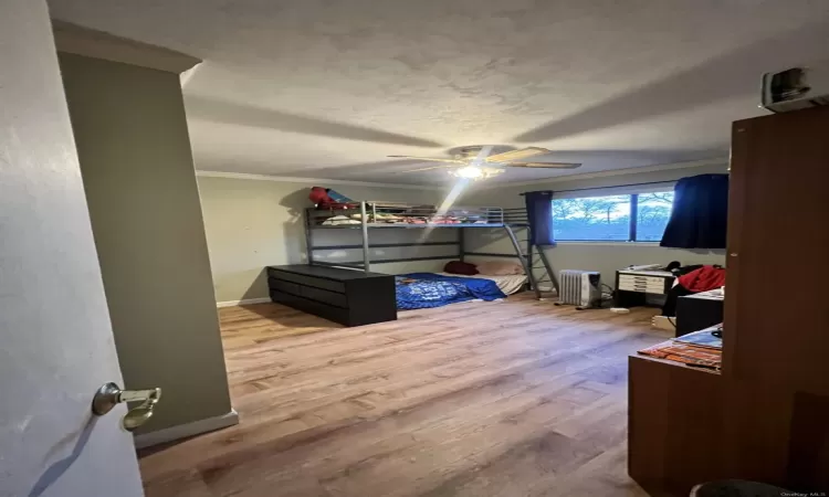 Bedroom featuring radiator heating unit, ceiling fan, light hardwood / wood-style flooring, and ornamental molding