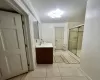 Bathroom featuring tile patterned flooring, toilet, vanity, and walk in shower