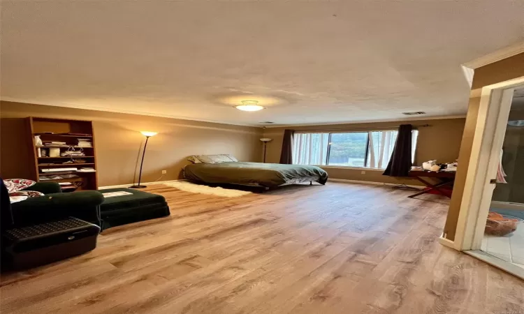 Bedroom featuring hardwood / wood-style floors, a textured ceiling, and ornamental molding