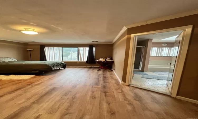 Unfurnished bedroom featuring hardwood / wood-style flooring and ornamental molding