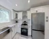 Kitchen featuring tasteful backsplash, white cabinets, wall chimney exhaust hood, and appliances with stainless steel finishes