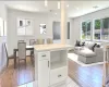 Kitchen with a center island, white cabinets, decorative light fixtures, light hardwood / wood-style floors, and light stone counters