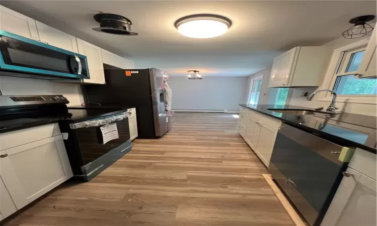 Kitchen featuring light hardwood / wood-style flooring, white cabinets, and stove