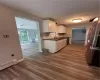 Kitchen featuring hardwood / wood-style floors, baseboard heating, sink, white cabinetry, and refrigerator