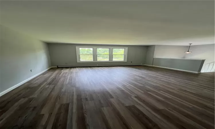 Spare room featuring a baseboard radiator and dark wood-type flooring