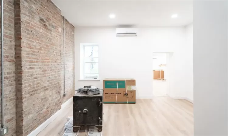 Empty room featuring an AC wall unit, hardwood / wood-style flooring, and brick wall