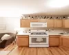 Kitchen featuring sink, light hardwood / wood-style flooring, white appliances, and light brown cabinets