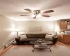 Living room with ceiling fan, a baseboard heating unit, and light wood-type flooring