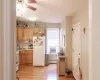 Kitchen featuring white appliances, light brown cabinetry, sink, light wood-type flooring, and a baseboard radiator