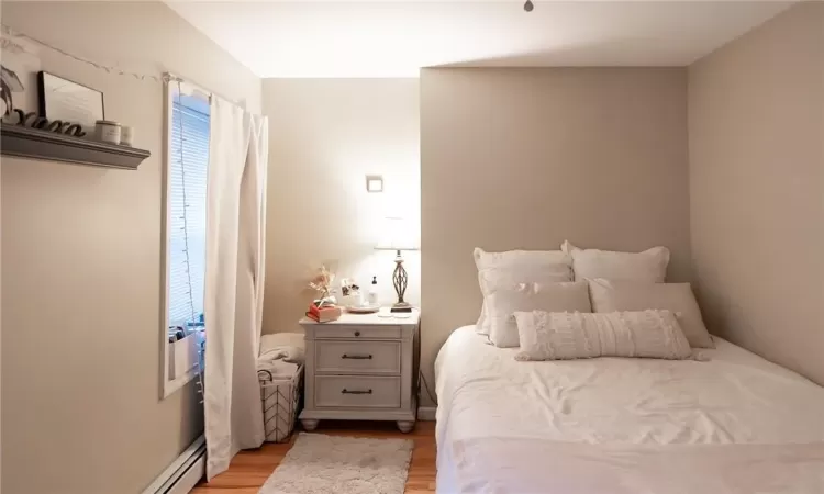 Bedroom featuring a baseboard radiator and light hardwood / wood-style flooring