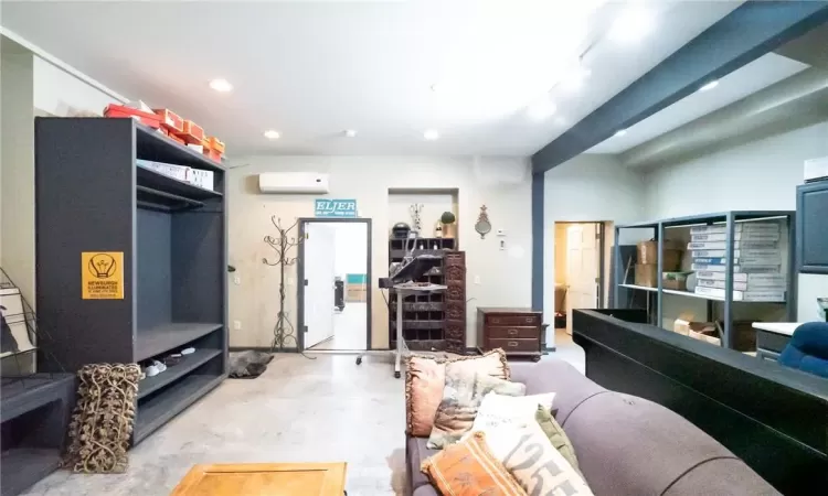 Living room and retail space featuring a wall mounted AC and concrete flooring