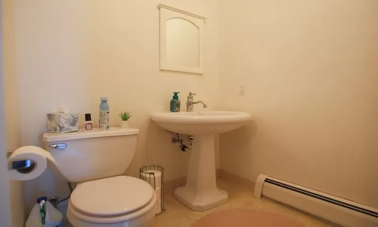 Bathroom with tile flooring, baseboard heating, and toilet