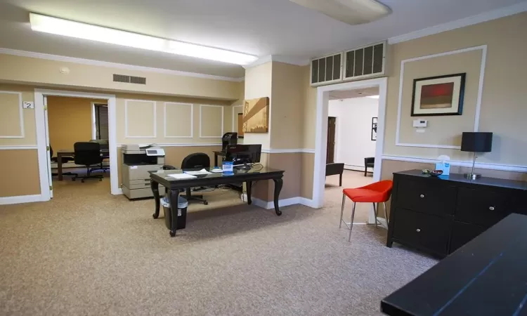 Home office with light colored carpet and crown molding