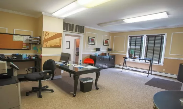 Carpeted office space featuring crown molding and a baseboard radiator